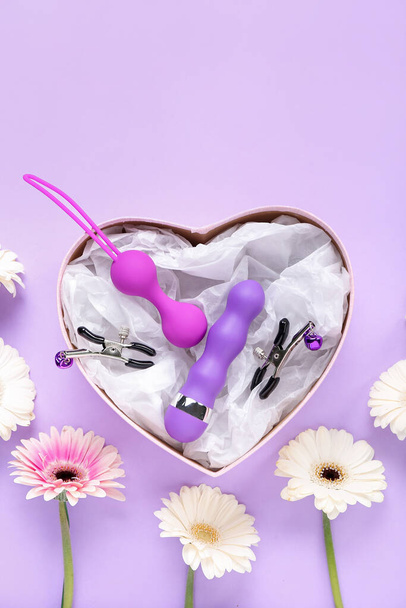 Scatola regalo con giocattoli del sesso e fiori su sfondo lilla - Foto, immagini