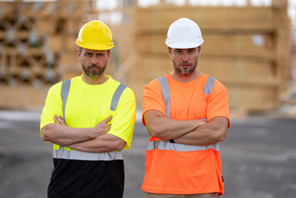 Construction workers at construction site. Serious men wearing safety vests and construction helmets. Construction foreman and builder. Civil engineers keeping arms crossed. - Foto, Imagem