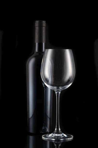 Wine bottle and wine glass in front of a black backgound - Foto, Imagen