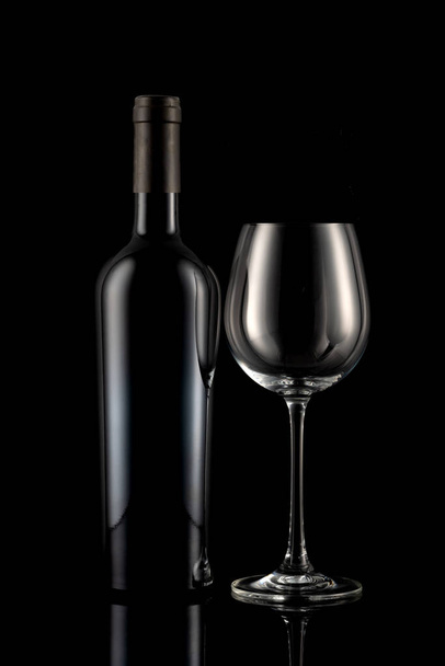 Wine bottle and wine glass in front of a black backgound - Photo, image