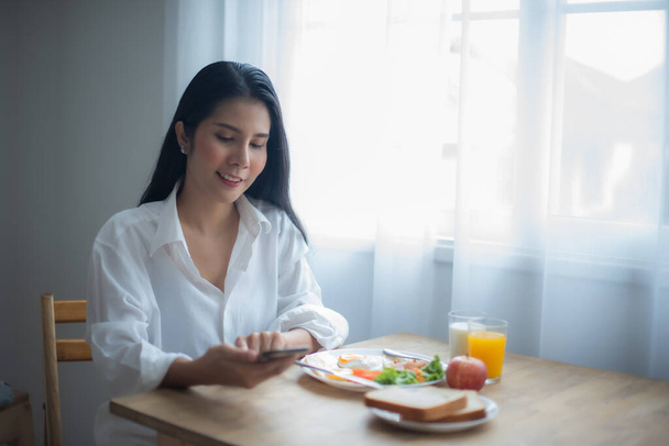 Beautiful asian girl seemed completely at ease and happy enjoying the moment her breakfast and the conversation with her friend. - Photo, Image