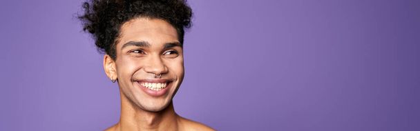 Young man model posing and smiling portrait. Transgender adult person lifestyle. Attractive latin american male on purple background. Trans gender identity. Sensitive, sexy and strong guy - Fotó, kép