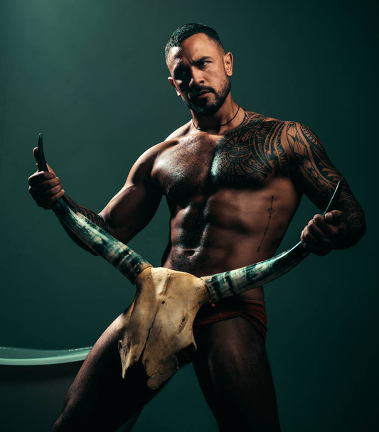Improving male sexual performance. Sexy hispanic macho with muscular body and sexual nature holding animals skull and horns. Sexi latino man showing his sexual desire and attraction. - Zdjęcie, obraz