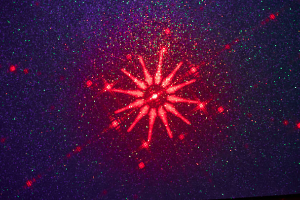 Op een donkerblauwe achtergrond in fijne korrels, een patroon van rode sterren - Foto, afbeelding