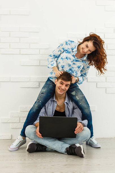 Couple Use Laptop Computer, while Sitting on the Living Floor room of their Apartment. Boyfriend and Girlfriend Talk, Shop on Internet, Choose Product to Order Online, Watch Streaming Service - Photo, Image
