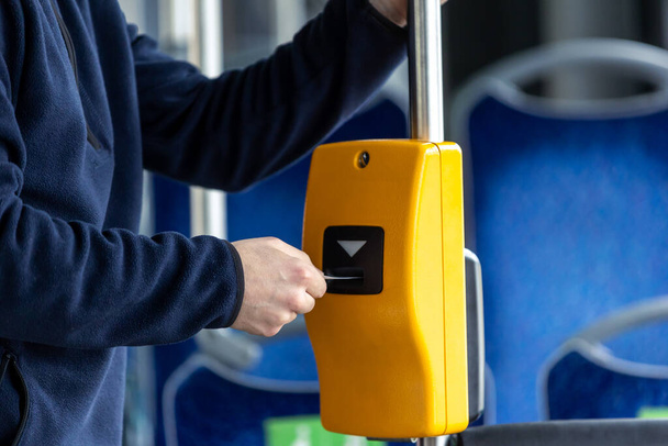 Young man hand inserts the bus ticket into a validator, validating and ticking - Foto, Imagem