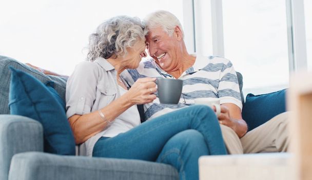 Настоящая любовь никогда не стареет. пожилая пара наслаждается расслабляющим кофе-брейком на диване дома - Фото, изображение