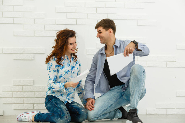 Smiling husband and wife sit taking care of utility bills and house maintenance documents, happy young couple read paperwork. - Foto, imagen