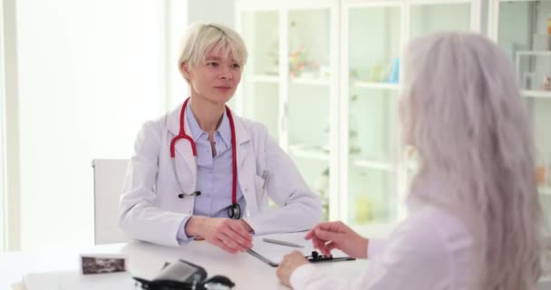 Klinik toplantısında gülümseyen kadın doktor olgun bir kadınla el sıkışıyor. Yaşlı bir hasta sağlık sigortası anlaşması yapıyor. - Video, Çekim