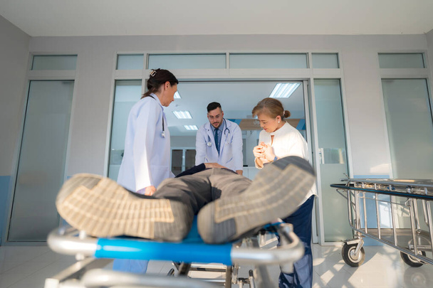 The emergency patient lies in a hospital bed with a doctor performing an urgent examination. - Foto, Bild