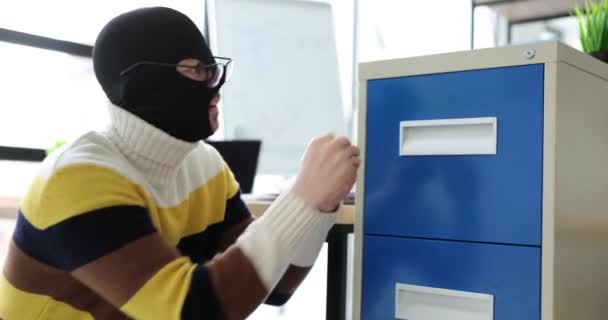 Man thief criminal in balaclava opens shelf steals information from office. Theft of company financial information - Footage, Video