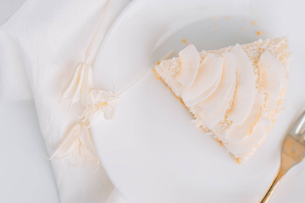White cheesecake with coconut flavor on plate with fork on white background with napkin. - Photo, image