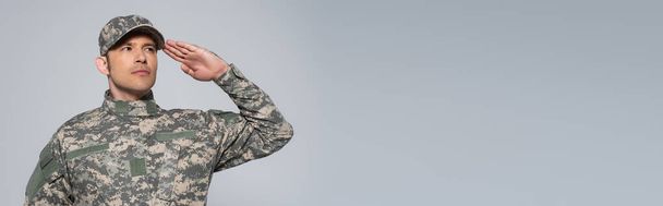 American soldier in military uniform with cap saluting during memorial day holiday isolated on grey, banner  - Фото, зображення
