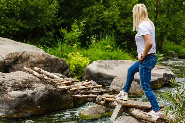 Μια γυναίκα διασχίζει ένα ποτάμι από πέτρες.. - Φωτογραφία, εικόνα