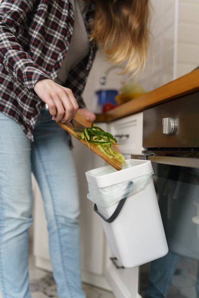Woman throwing compostable food peels in a bokashi bin with compost and bran - Fotó, kép