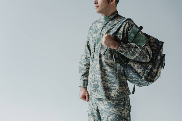 levágott kilátás katona katonai egyenruhában áll hátizsák elszigetelt szürke  - Fotó, kép