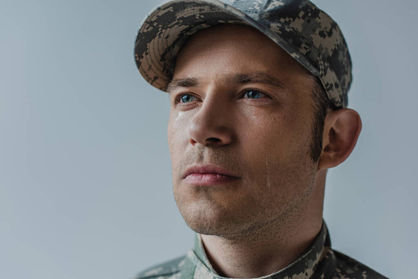 brave soldier in military uniform with teardrop on face isolated on grey  - Photo, Image