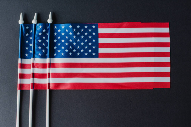 tendido plano de tres banderas americanas con estrellas y rayas aisladas en negro  - Foto, Imagen
