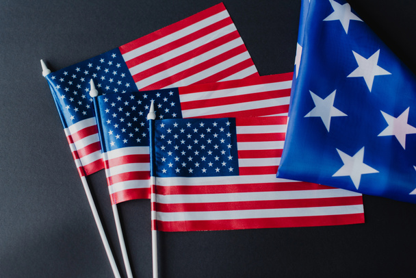 top view of three American flags near folded fabric with stars during memorial day isolated on black  - Fotó, kép
