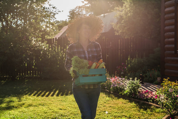 agricultor que lleva la caja de verduras recogidas
 - Foto, Imagen