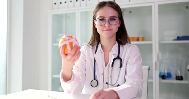 Nutricionista médico sostiene naranja y cinta métrica. Dieta y alimentación saludable - Imágenes, Vídeo