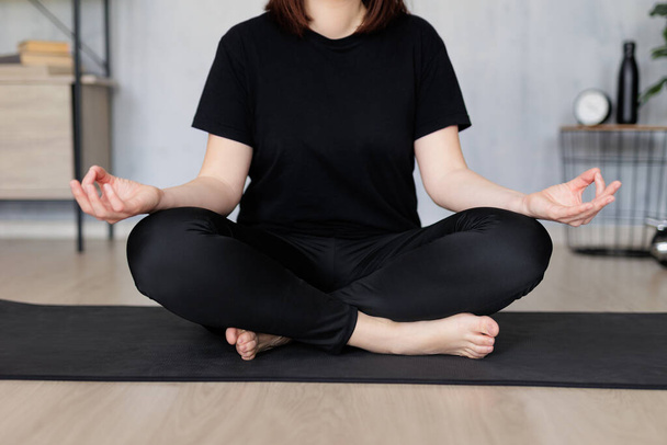 koncepcja jogi i medytacji - kobieta uprawiająca jogę siedząca na macie w domu - Zdjęcie, obraz