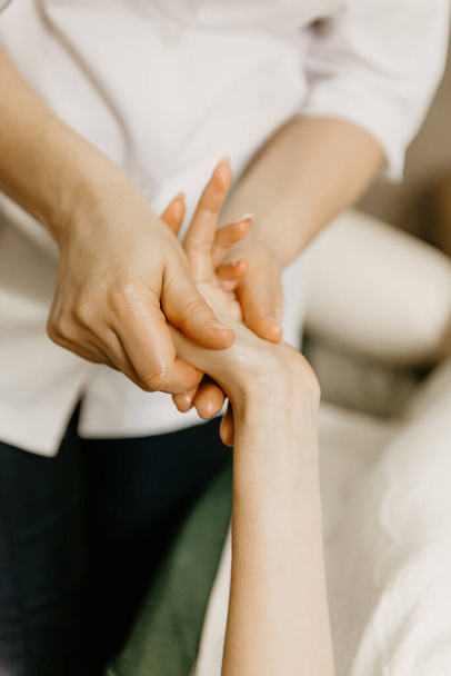 Professional manual therapist makes the hands of a young woman. Treatment of muscles and joints of the hands. - Fotó, kép