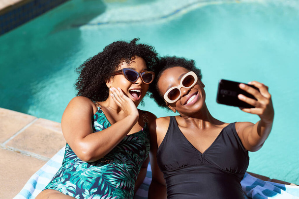 Due amici sdraiati a bordo piscina che fanno selfie in costume da bagno, estate positiva per il corpo. Foto di alta qualità - Foto, immagini