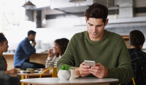 Давай выясним, где остальные. красивый молодой человек, использующий мобильный телефон в кафе - Фото, изображение