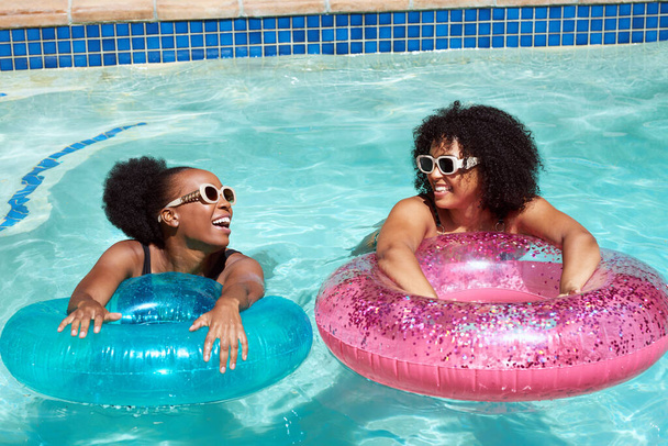 Two Black friends practice kicking in the swimming pool with inflatable rings. High quality photo - Photo, Image