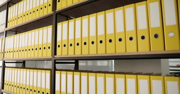 Carpetas de negocio amarillas idénticas en estante en archivo. Documentación y archivo empresarial - Imágenes, Vídeo