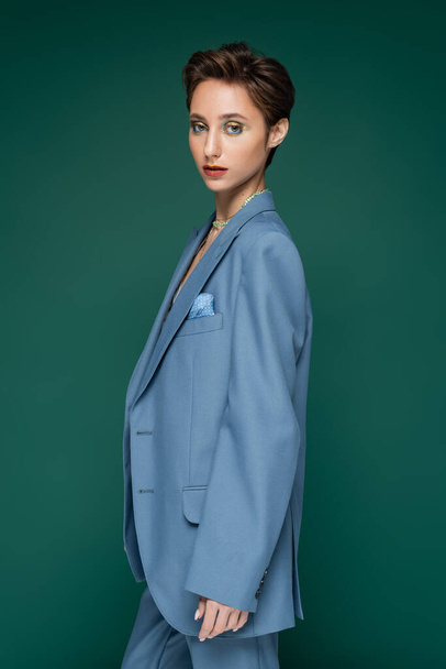 stylish woman in blue formal wear posing on turquoise green background  - Photo, Image