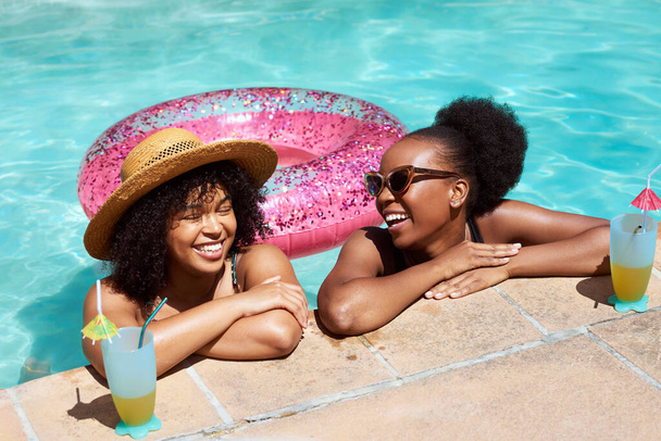 Two Black friends lean on the side of the pool, relaxing in water with mocktails. High quality photo - Photo, Image