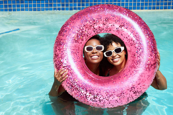 Deux amis noirs posent avec leurs têtes à l'intérieur anneau de piscine gonflable rose. Photo de haute qualité - Photo, image