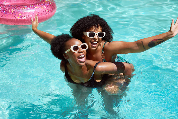 Dos amigos negros divirtiéndose en la piscina, nadando a cuestas riendo divirtiéndose. Foto de alta calidad - Foto, Imagen