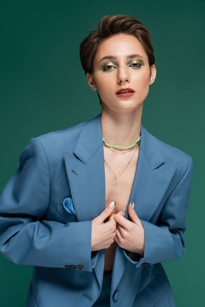 young well dressed woman with short hair posing in blue jacket on turquoise background  - Photo, Image