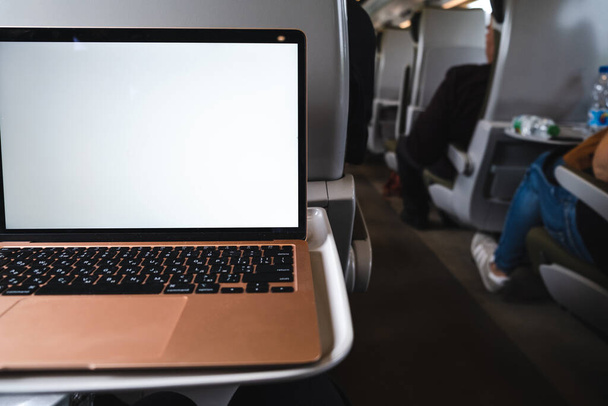 portátil con pantalla blanca se sienta en una mesa en un tren - Foto, Imagen