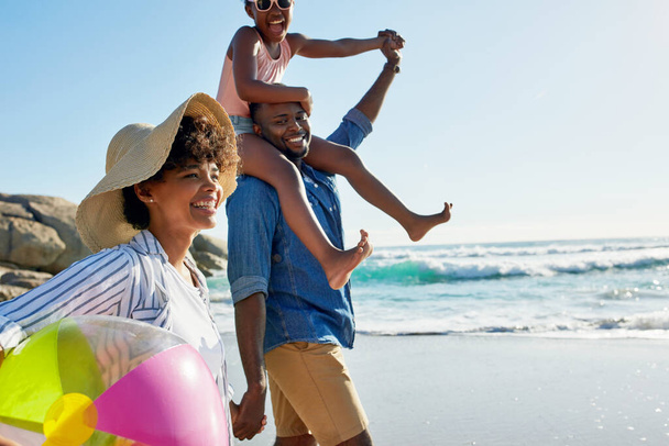 Tratar a la familia con unas vacaciones de verano. una niña adorable que va a dar un paseo con sus padres en la playa - Foto, Imagen