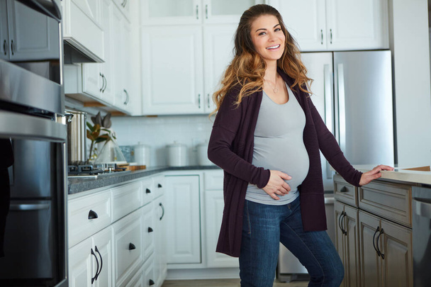 Ive always wanted to be a mother. Cropped portrait of an attractive young pregnant woman standing in her kitchen at home - Photo, image