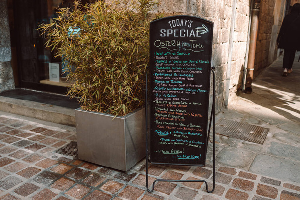 Menu restaurante preto quadro na rua. Um quadro de menu com uma lista de pratos em frente a um restaurante em uma rua pedonal em Pisa, Itália. Foto de alta qualidade  - Foto, Imagem