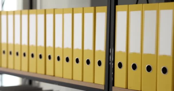 Gelbe Ordner mit Dokumenten reihen sich in Regalen im Büro aneinander. Geschäftsunterlagen des Unternehmens - Filmmaterial, Video