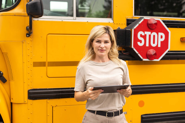 Portrait of female teacher near the school bus. - Φωτογραφία, εικόνα