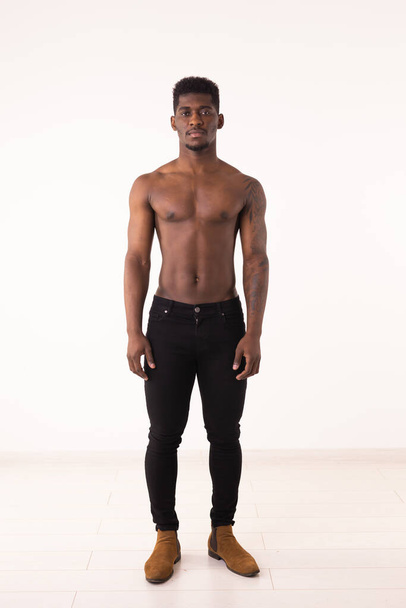 Africano americano culturista hombre desnudo muscular torso usando pantalones de entrenamiento sobre fondo blanco - Foto, imagen