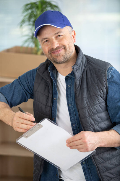 cheerful removals man holding a clipboard - Foto, imagen