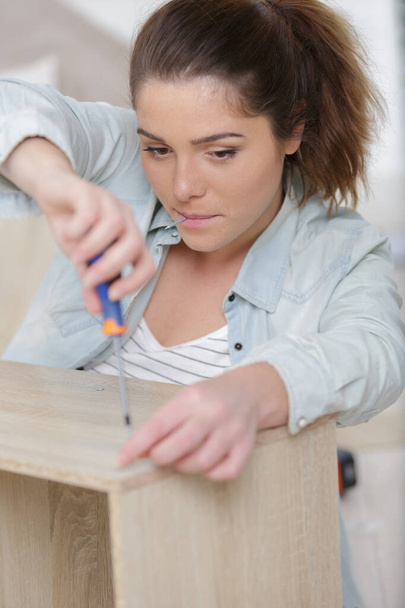 young woman repairing furniture at home - Foto, afbeelding
