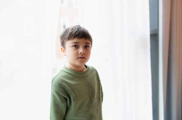 Portret Kid jongen met glimlachend gezicht kijken omhoog staan achter kant gordijn met helder licht in de ochtend, Positieve kinderen concept - Foto, afbeelding