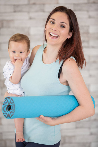 happy woman holding baby and exercise mat - Foto, Imagem