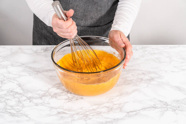 Mezclar los ingredientes en un tazón de vidrio grande para hornear pastel de manojos de calabaza de chocolate con esmalte de caramelo. - Foto, Imagen