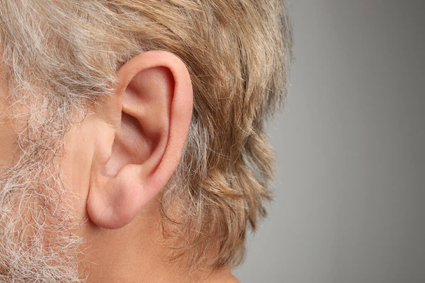 Closeup view of man against light grey background, focus on ear - Foto, afbeelding