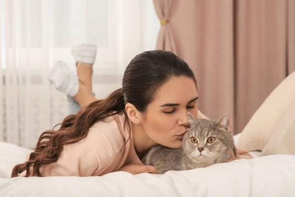 Junge Frau küsst ihre entzückende Katze zu Hause - Foto, Bild